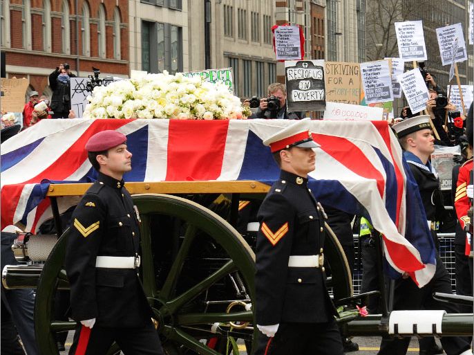 epa03665210 A group of demonstrators wave placards in the background as the gun carriage carrying the Union flag-draped coffin of former British Prime Minister Margaret Thatcher crosses Ludgate Circus, a short distance from St. Paul's Cathedral in central London 17 April 2013 during her ceremonial funeral. Baroness Thatcher died after suffering a stroke at the age of 87 on 08 April 2013. EPA/FACUNDO ARRIZABALAGA
