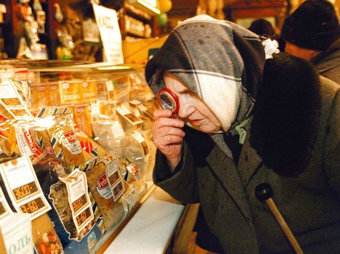 An old Russian lady (babushka) uses a magnifying glass to compare new and old price lists in the window of Yeliseevsky shop in Moscow 04 JAN. .All price lists have been changed in shops,and although the new slimline ruble went in theory in circulation from midnight 01 January,it will see light of day once the major banks reopen on January 05,because of New Year holidays
