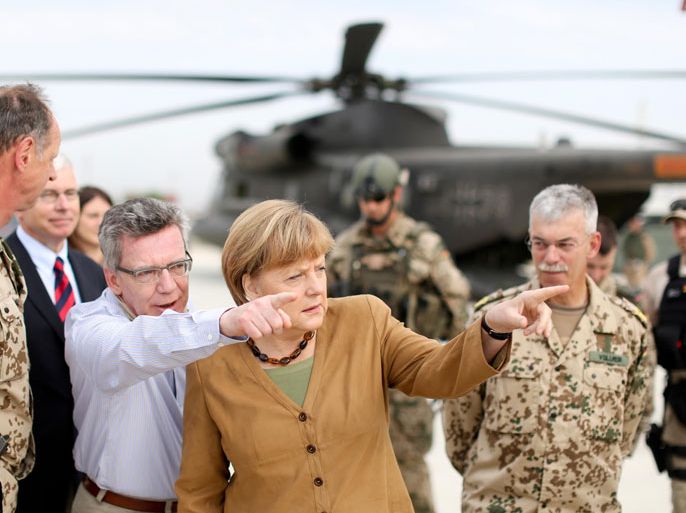436 - Kunduz, -, AFGHANISTAN : German Defence Minister Thomas de Maiziere (3dL) and Chancellor Angela Merkel (C) gesture next to ISAF Regional Commander North German general Joerg Vollmer (R), on May 10, 2013 upon arrival at the German military base in Kunduz during their visit in Afghanistan. Their surprise visit comes six days after a German soldier was killed and another wounded in an attack by insurgents in northern Afghanistan.