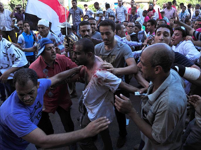 Egyptians help a wounded man following clashes between supporters and opponents of President Mohamed Morsi in the coastal city of Alexandria on June 28, 2013. Supporters and opponents of Morsi took to the streets for rival protests a year after his election, as clashes in Alexandria raised fears of widespread unrest. Fervent displays of emotion on both sides underline the bitter divisions in Egypt, with Morsi's opponents accusing him of hijacking the revolution and his supporters vowing to defend his legitimacy to the end. AFP PHOTO/STR