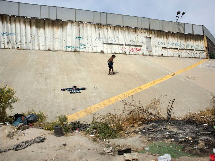 epa03719805 (06/17) A homeless man with truncated arms walks next to the US-Mexico border wall on the US side of the international boundry (yellow line), in Tijuana, Mexico, 03 May 2013. Heightened US border security and record numbers of deportations from the US have created a growing population of people who live homeless in Mexican cities that border with the United States. Many had lived for years undocumented in the US and have little or no family and other support in Mexico, and are subject to fall into depression, substance abuse and crime. Tijuana, Mexico, borders on the US city of San Diego, California. EPA/DAVID MAUNG PLEASE REFER TO ADVISORY NOTICE(epa03719799) FOR FULL FEATURE