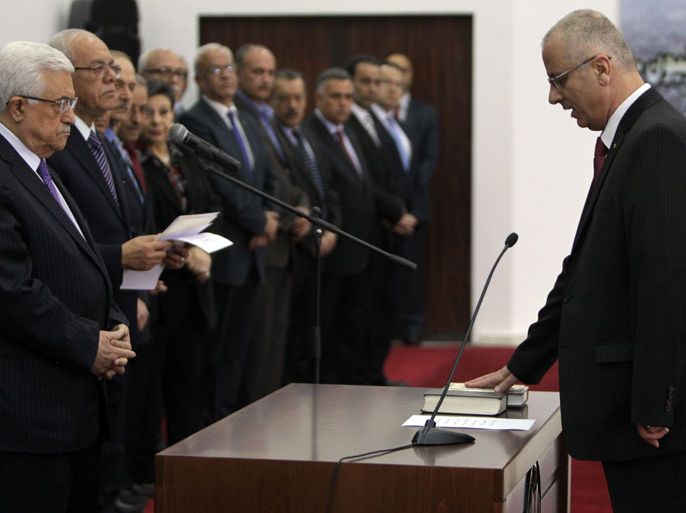 : Newly appointed Palestinian prime minister, Rami Hamdallah (R) is sworn in along with the new government, in front of Palestinian president Mahmud Abbas (L), at his headquarters in Ramallah, on June 6, 2013. The 24-member cabinet included some changes, notably the appointment of two deputy premiers and a new finance minister, but remains largely unchanged from its predecessor. AFP PHOTO/ABBAS MOMANI