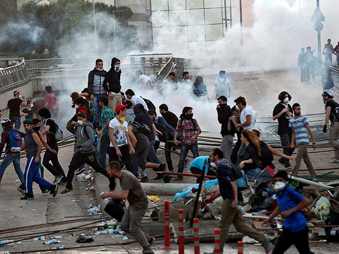 epa03729819 Protestors run away from Turkish riot police (out of frame) using tear gas near Taksim Square in Istanbul, Turkey, 03 June 2013. More than 2,300 people have been injured and one person killed during four days of fierce clashes between protesters and police in Turkey, according to a doctors' association, as the prime minister blamed 'extremist elements' for the riots. More than 1,480 people have been wounded in clashes in Istanbul, the country's largest city, with some 800 more injured in the capital Ankara and the Aegean city of Izmir. EPA/SEDAT SUNA EPA/SEDAT SUNA