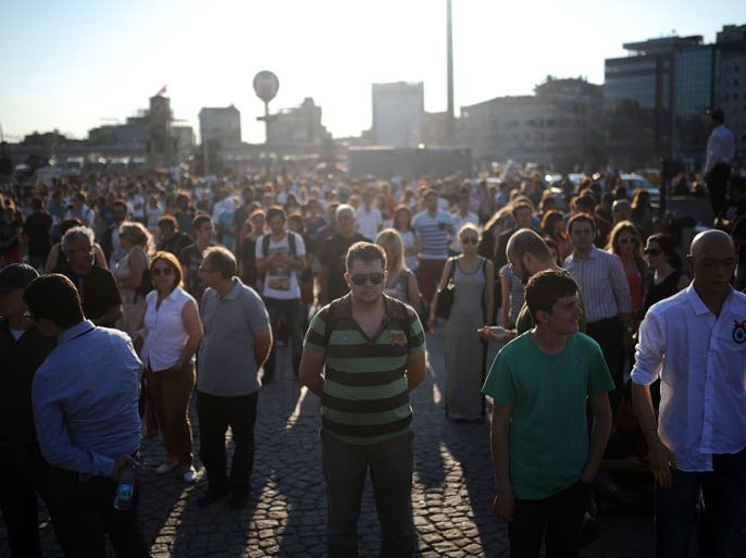 People stand on the flashpoint Taksim square in Istanbul on June 18, 2013 during a wave of new alternative protests. Prime Minister Recep Tayyip Erdogan on June 18 claimed victory over Turkey's anti-government protesters after a heavy crackdown on the movement, as police raided homes and arrested dozens of demonstrators to stamp out nearly three weeks of unrest. In Istanbul, dozens of demonstrators switched to silent protests, standing still in quiet defiance in the main Taksim Square located next to the Gezi Park