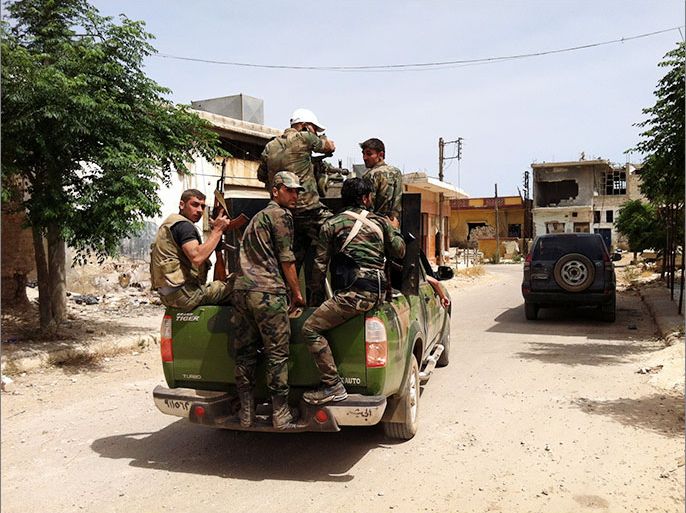 A picture taken on June 7, 2013 shows Syrian army soldiers patrol a street in the village of Buweida, north of Qusayr, in Syria's central Homs province. Forces loyal to President Bashar al-Assad have now seized all of the Qusayr area in central Syria, state television reported on Saturday, as troops overran the last rebel bastion in the area. AFP PHOTO / STR
