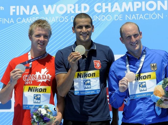 Gold medalist Oussama Mellouli, from Tunisia stands with silver medalist Canada's Eric Hedlin, left, and bronze medalist Thomas Lurz of Germany, right, after the men's 5km open water swim competition at the FINA Swimming World Championships in Barcelona, Spain, Saturday, July 20, 2013.
