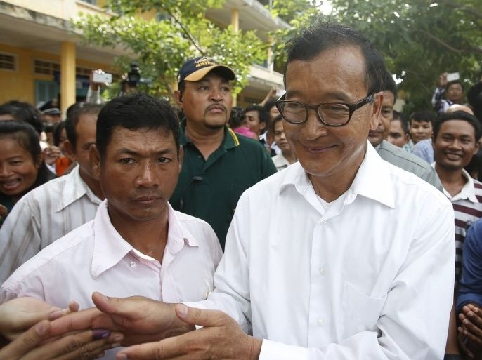 Sam Rainsy (C), president of the Cambodia National Rescue Party (CNRP), visits a polling station during the general elections at a pagoda in Phnom Penh July 28, 2013. The Cambodian People's Party (CPP) of long-serving Prime Minister Hun Sen won Sunday's election, taking 68 seats to the main opposition party's 55, the government's main spokesman said.