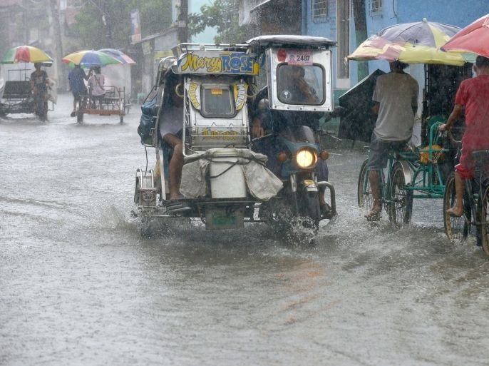 Residents commute along a flooded stretch of road during heavy rain in the suburbs of Manila on August 12, 2013. The strongest typhoon to hit the Philippines this year flattened houses and triggered landslides in remote towns on August 12, killing at least one person and leaving 23 others missing, authorities said.