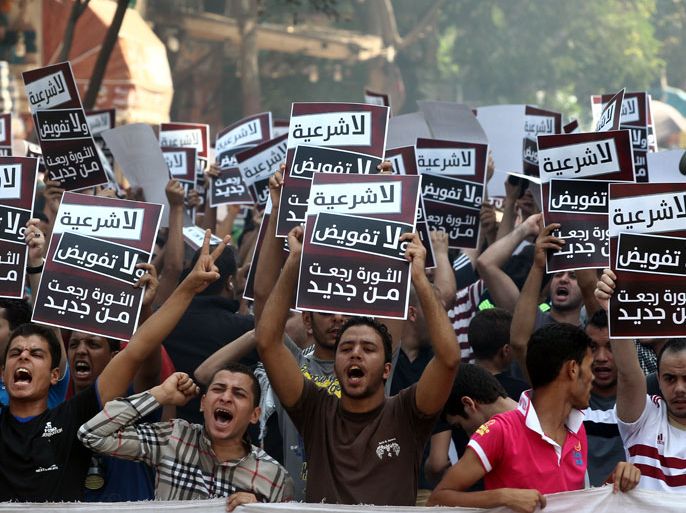 epa03843411 Egyptian activitsts hold placards reading 'no legitimacy, no authorization, the revolution is back' in Arabic as they protest against the Egyptian Army and the Muslim Brotherhood in Giza, Egypt, 30 August 2013. Egyptian groups called for mass protests on 30 August