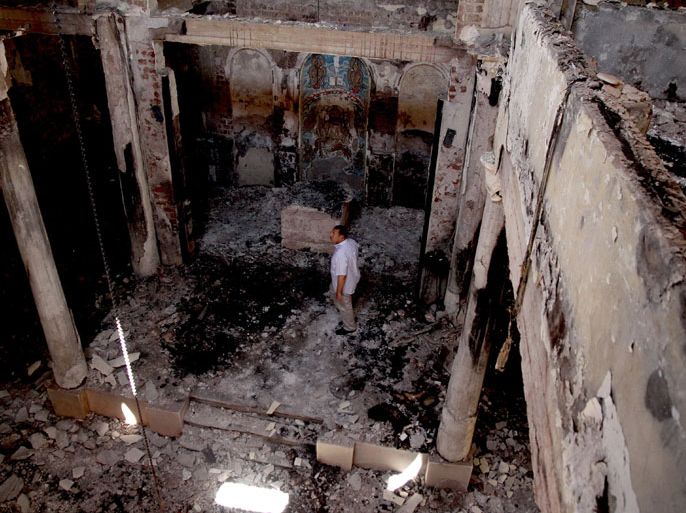 epa03830789 A man stands amid rubble at the St. John Church that was burnt by mobs in Abnoub, east Assiut, about 354 kilometers south of Cairo, Egypt, 19 August 2013. The church was allegedly set ablaze by Islamists on 14 August after security forces clamped down on two protest camps in Cairo filled with supporters of ousted president Mohamed Morsi. The Coptic church on 16 August expressed its support for police and army forces in their 'fight against terrorism' after Christian properties and churches were attacked and torched by Islamists earlier this week. EPA/GIRO MAIS