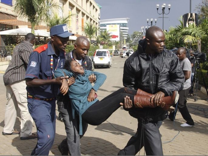 A security officer helps a wounded woman outside the Westgate Mall in Nairobi, Kenya Saturday, Sept. 21, 2013, after gunmen threw grenades and opened fire during an attack that left multiple dead and dozens wounded. A witness to the attacks on the upscale shopping mall says that gunmen told Muslims to stand up and leave and that non-Muslims would be targeted.