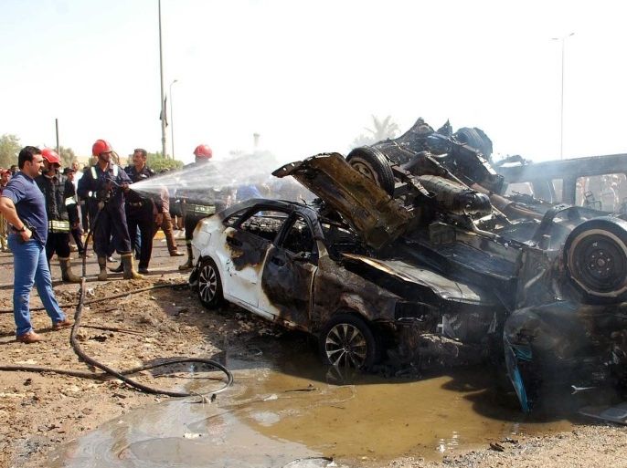 A picture taken on September 15, 2013 shows Iraqis and firefighters gathering near burnt vehicles at the scene of a car bomb explosion in Nasiriyah, south of the Iraqi capital Baghdad. A wave of attacks across Iraq, the deadliest of which struck south of Baghdad, killed 26 people and left dozens more wounded, security and medical officials said.