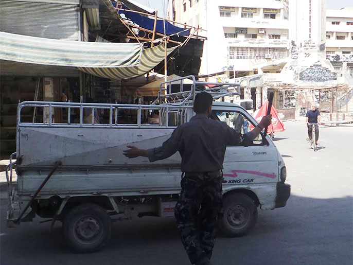 ‪أحد عناصر الشرطة الثورية يفسح المجال أمام سيارة بالغوطة الشرقية‬ (الجزيرة)