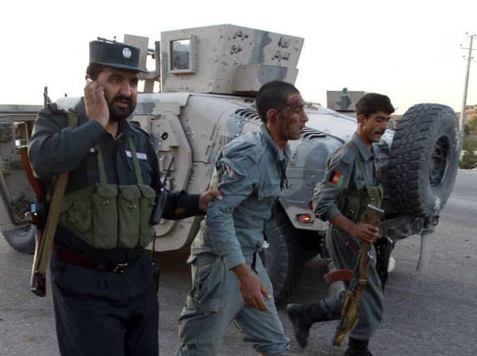 A wounded policeman (C) is helped from the scene of an attack at the U.S. Consulate in the western Afghanistan city of Herat September 13, 2013. At least three people were killed when insurgents attacked the U.S. consulate in Herat on Friday, detonating a powerful truck bomb outside the front gates and launching a gunbattle with security forces, officials said.