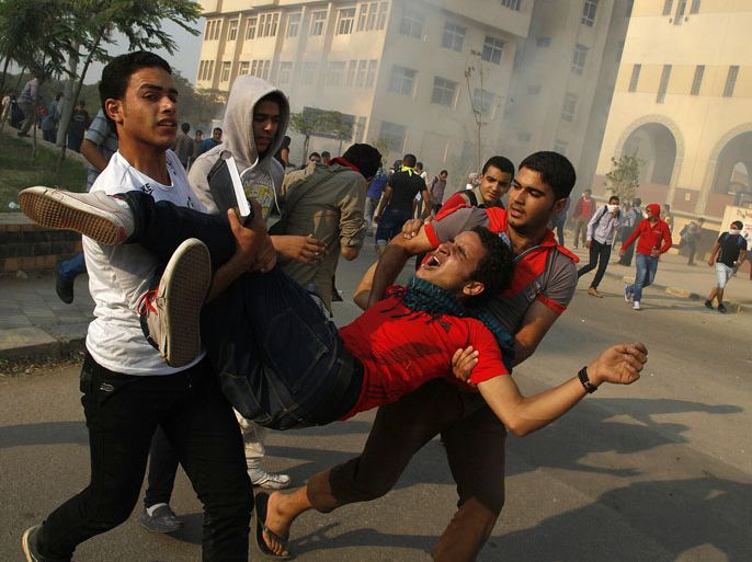 GUE1694 - Cairo, -, EGYPT : Student supporters of ousted president Mohamed Morsi and the Muslim brotherhood carry a comrade injured during clashes with Egyptian security forces outside al-Azhar university in Cairo on October 28, 2013. Egyptian security forces fired tear gas to disperse students protesting in support of ousted Islamist president Mohamed Morsi, security officials said. TOPSHOTS/AFP PHOTO/MOHAMMED ABDEL MONEIM