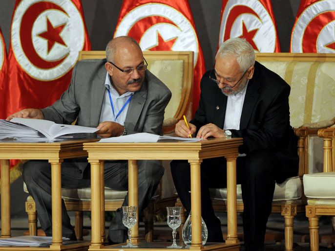 Tunisia's ruling Islamist Ennahda party's leader Rached Ghannouchi (R) signs documents during a meeting as part of the dialogue between Tunisia's ruling Islamists and the opposition aimed at ending a two-month crisis on October 5, 2013 at the Palais des Congres in Tunis. Ennahda and the opposition signed a roadmap for the creation of a government of independents within three weeks. AFP PHOTO FETHI BELAID