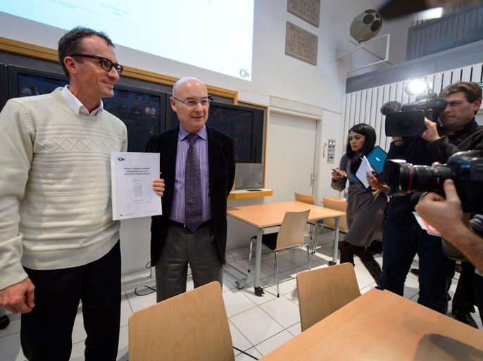 Head of the Institute for Radiation Physics (IRA) François Bochud (G) holds the rapport next to the head of the Lausanne University Centre of Legal Medicine (CURML) Patrice Mangin (R) during a press conference on November 7, 2013 in Lausanne after the Swiss scientists have concluded that Palestinian leader Yasser Arafat probably died from polonium poisoning, according to a text of their findings published by Al-Jazeera television. AFP PHOTO
