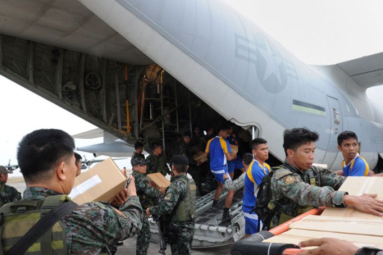 TA1474 - Tacloban, -, PHILIPPINES : Philippine and US military personnel unload relief goods from a US military C-130 plane at Tacloban airport in the central Philippines on November 11, 2013, after Super Typhoon Haiyan devastated the city on November 8. US military planes on November 11 joined a frantic effort to rescue famished survivors of the monster typhoon that may have killed 10,000 people in the Philippines, as local security forces struggled to contain looting. AFP PHOTO / TED ALJIBE