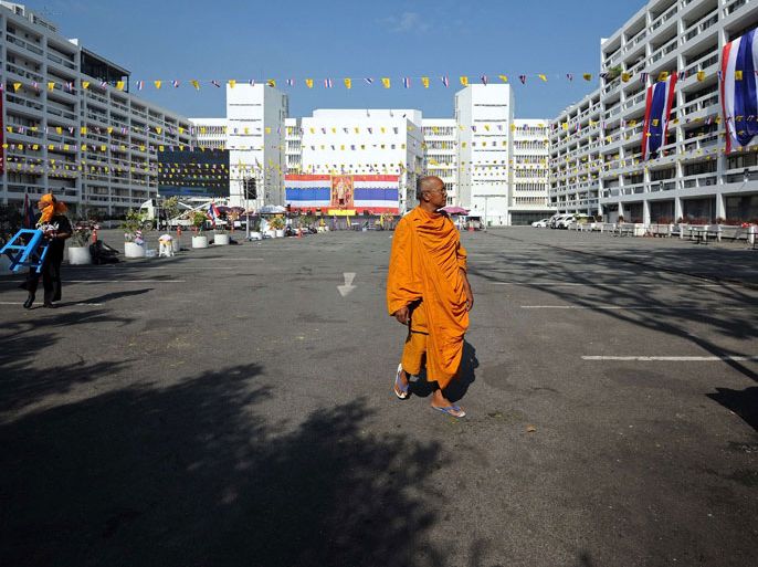 Bangkok, -, THAILAND : TOPSHOTSA Thai Buddhist monk walks past a near empty parking lot of the Finance Ministry occupied by anti-government protesters in Bangkok on December 6, 2013. Thai opposition protesters were preparing on December 6 to relaunch their campaign to overthrow the government after a temporary truce in the strife-hit capital for the birthday of the country's revered king. AFP PHOTO / Indranil MUKHERJEE
