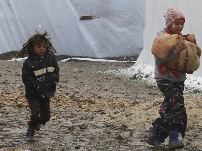 طفلان من اللاجئين السوريين في مدينة زحلة بلبنان يحاولان الاحتماء من عاصفة ثلجية عام 2013 (رويترز)