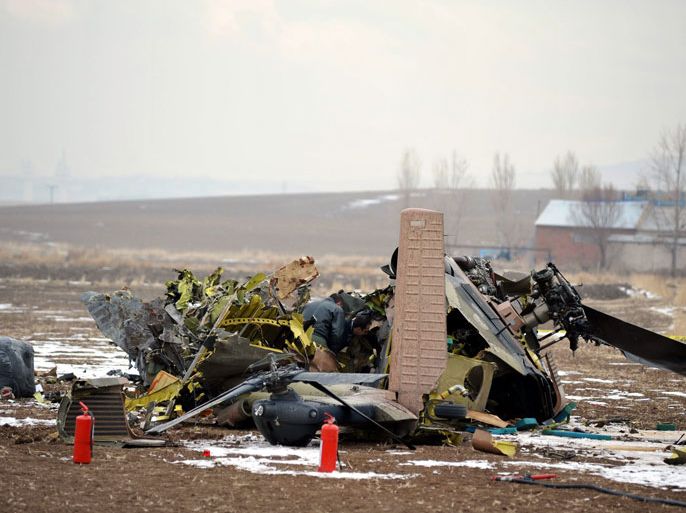 Turkish officials examine the wreckage of a Turkish military S-70 Sikorsky helicopter which crashed in the outskirts of the capital Ankara, killing all four of its crew members, on December 17, 2013 . The S-70 Sikorsky helicopter was on a training mission when it hit the high-voltage transmission cables and crashed into a field 19 kilometres (11 miles) from the city centre, the state-run Anatolia news agency reported. AFP PHOTO
