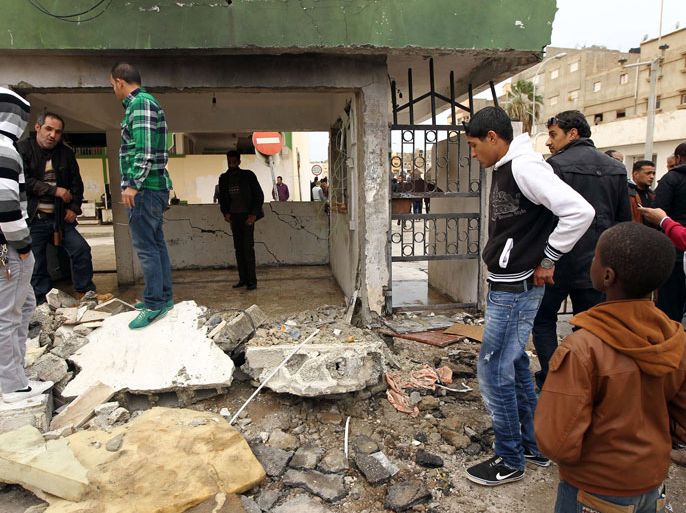 Libyans inspect the scene after an explosive device was detonated at a security gurad post outside a court in the al-Majora area, south of the eastern coastal Libyan city of Benghazi on January 6, 2014. A member of the security staff was killed and another person was wounded in the attack.