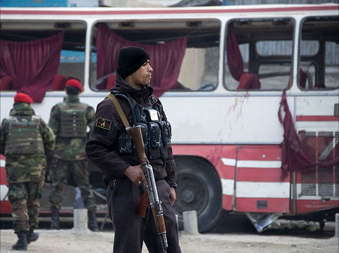 An Afghan policeman stands next to a damaged bus at the site of a suicide attack on the Jalalabad road in Kabul on January 12, 2014. A suicide bomber riding a bicycle targeted a police bus in Kabul causing several