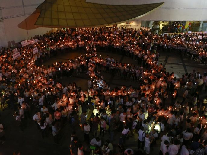 People hold candles as they form a peace sign during an anti-violence campaign in central Bangkok January 10, 2014. Thailand on Friday played down talk of a military coup ahead of a planned "shutdown" of the capital next week by protesters trying to overthrow Prime Minister Yingluck Shinawatra and said life would go on much as normal. REUTERS/Soe Zeya Tun (THAILAND - Tags: POLITICS CIVIL UNREST)