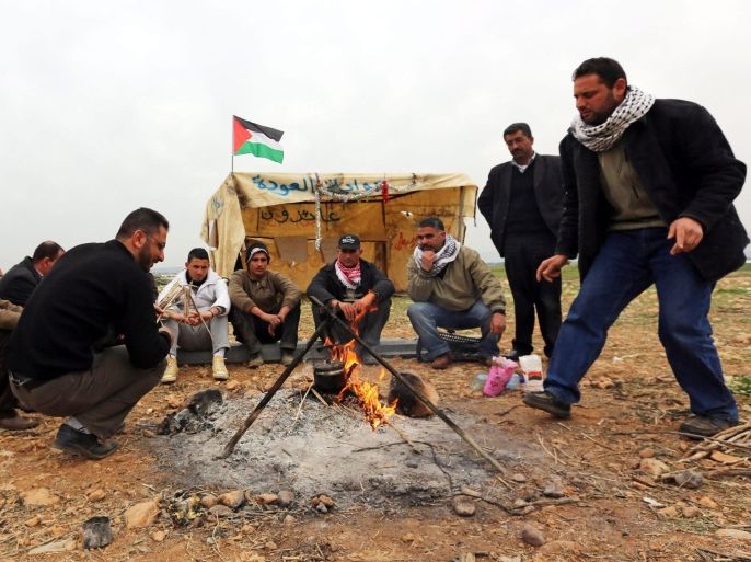 Palestinian activists warm themselves beside a fire at the site of a tent village in the Jordan Valley near the West Bank village of Bardala, 02 February 2014. Palestinian activists protested against the ongiong peace talks with Israel.