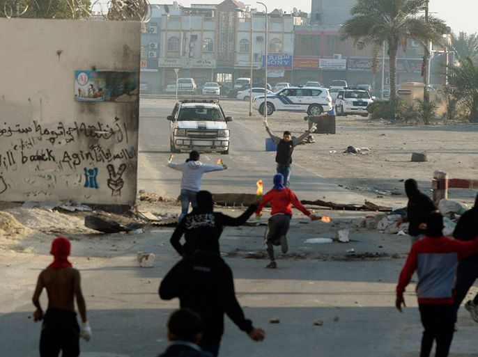 epa04075542 Protesters carry petrol bombs as they clash with police in Maqsha village, north of Manama, Bahrain, 13 February 2014