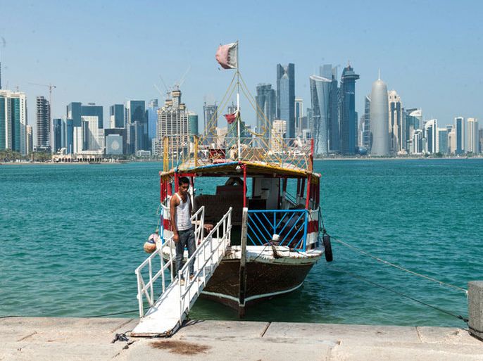 epa03895910 A crewman of a sightseeing boat for tourists waits for customers to board the the vessel at the Corniche beach promenade opposite the city's skyline, in Doha, Qatar, 04 October 2013. EPA/STR