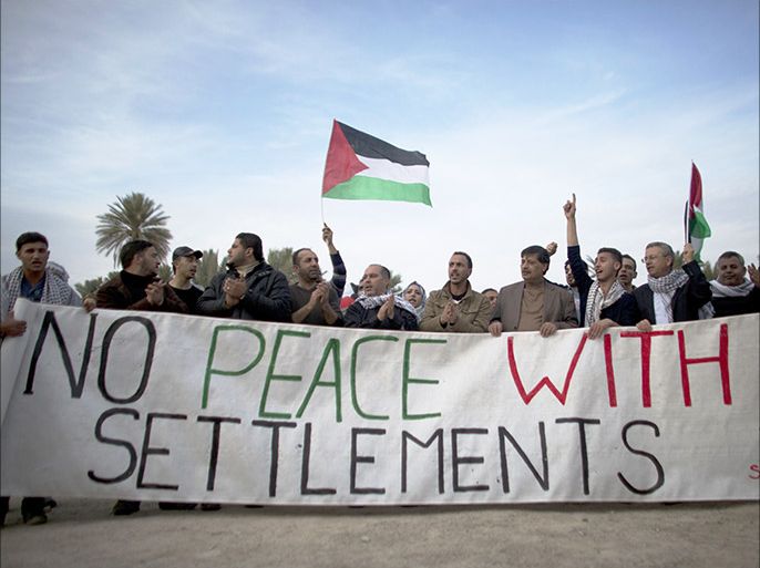 Palestinians and Israeli activists hold a banner reading "No peace with settlements" as they take part in a protest denouncing the repeated refusals of the Israeli Prime Minister to dismantle Jewish settlements, on January 31, 2014