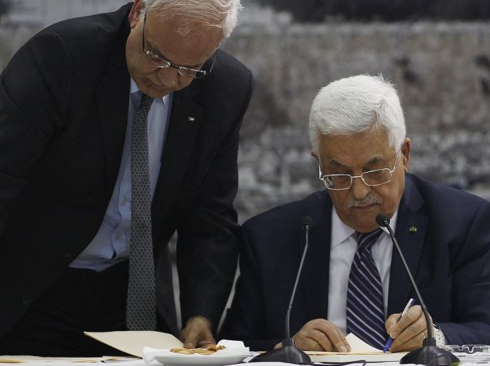 Palestinian chief negotiator Saeb Erekat (L) helps Palestinian President Mahmoud Abbas as he signs international conventions during a meeting with Palestinian leadership in the West Bank City of Ramallah April 1, 2014. Abbas signed more than a dozen international conventions on Tuesday citing anger at Israel's delay of a prisoner release, in a move jeopardised U.S. efforts to salvage fragile peace talks. REUTERS/Mohamad Torokman (WEST BANK - Tags: POLITICS)