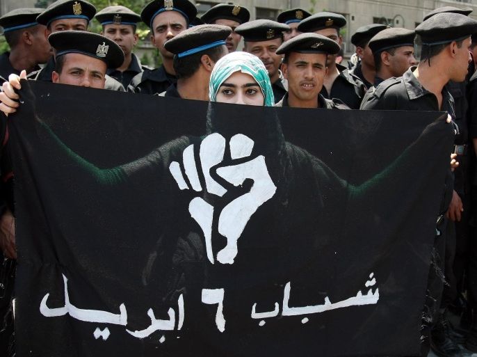 (FILE) A file photograph dated 03 May 2010 shows an Egyptian protestor holding up a flag that reads in Arabic 'The Youth of 6 April' as riot police stand behind her during in a rally at Tahrir Square in downtown Cairo, Egypt. A Cairo court on 28 April 2014, banned the opposition April 6 Youth Movement that was a catalyst in the uprising to oust president Hosni Mubarak in 2011. The court banned all activities of the movement, on charges of espionage and defaming the state. The April 6 group was launched in 2008, promoting the call for a nationwide strike to be held on April 6 in solidarity with workers' strikes. The same court, the Court for Urgent Matters, previously banned the Muslim Brotherhood as well as the activities of the Palestinian movement Hamas in Egypt.