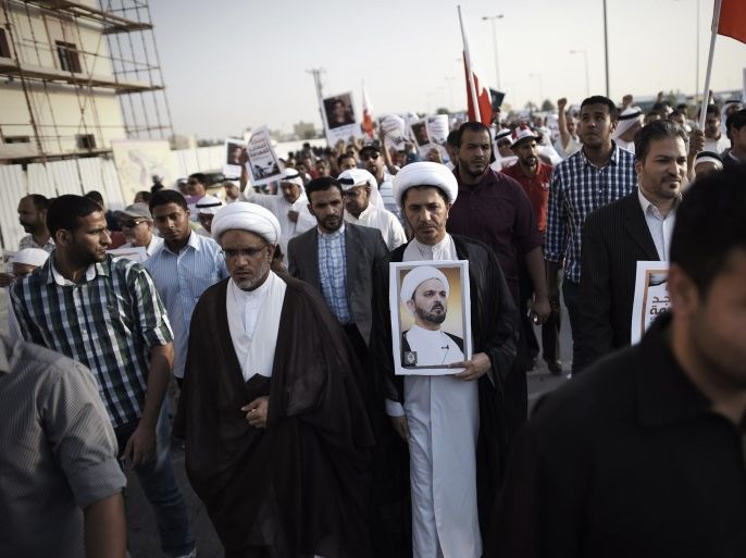 Bahrain's Al-Wefaq opposition group leader Sheikh Ali Salman (C) holds up a portrait of Bahraini cleric Shaikh Hussain Najati, who dropped his nationality and urged by Bahraini authorities to leave the country, during an anti-government protest in the village of Salmabad, south of the capital Manama, on April 18, 2014. Dozens of Shiites have been tried over incidents of unrest following Arab Spring-inspired protests in mid-February 2011, during which demonstrators called for reforms in the Sunni-ruled kingdom. AFP PHOTO/MOHAMMED AL-SHAIKH