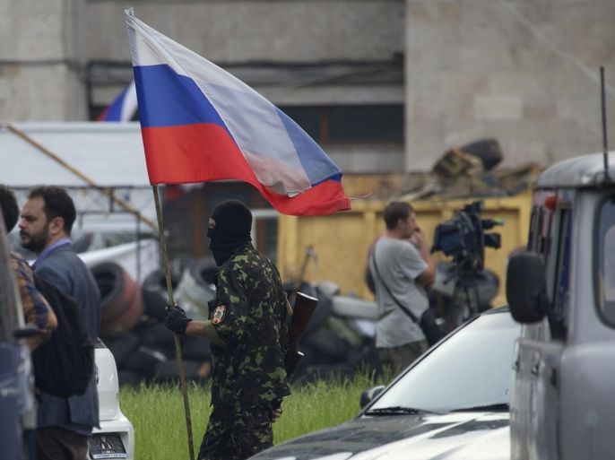 A Pro-Russian militia member carries a Russian flag outside the administrational building in Donetsk, Ukraine, on Thursday, May 29, 2014. Pro-Russian militia in eastern Ukraine shot down a government military helicopter Thursday amid heavy fighting around Slovyansk, killing 14 soldiers including a general. (AP Photo/Ivan Sekretarev)