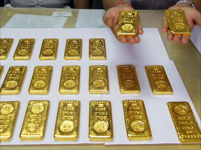 epa03958159 A customs officer (R) shows 24 gold bars to media after being seized at the Netaji Subhash Chandra Bose International Airport in Calcutta, Eastern India, 20 November 2013. As many as 24 gold bars weighing a kilogram each, lying unclaimed in two bags in an empty aircraft, were recovered by the airport officials while checking the aircraft on 19 November 2013. EPA/STR