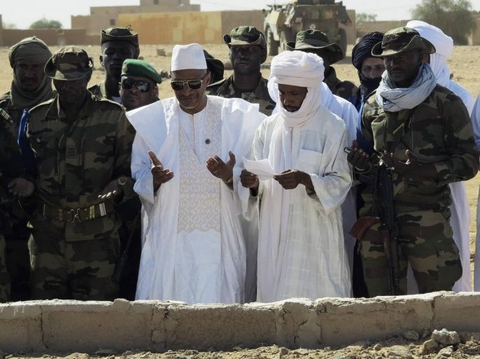 Malian Defense Minister Soumeylou Boubeye Maiga (2nd L) prays over a mass grave during a ceremony marking two years since Malian soldiers were killed in a massacre by radical Islamists, in Aguelhok, Mali, January 24, 2014. Picture taken January 24, 2014. REUTERS/Joe Penney (MALI - Tags: POLITICS CIVIL UNREST ANNIVERSARY)