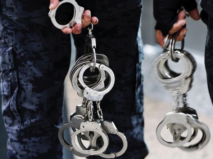 Immigration officers carry pairs of handcuffs at Kuala Lumpur International Airport March 12, 2014. REUTERS/Damir Sagolj (MALAYSIA - Tags: TRANSPORT CRIME LAW)