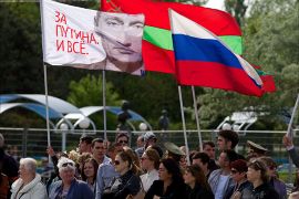 People carry a Russian flag (C) and a flag with a portait of Russia's President Vladimir Putin reading "We are for Putin!" in Tiraspol, the main city of Transdniestr separatist republic of Moldova, on May 9, 2014, during Victory Day celebrations. Transnistria, a small strip of land of 500,000 inhabitants in eastern Moldova, has won the support of Russia, a short war of independence after the collapse of the USSR in 1991. It is not recognized by the international community. AFP PHOTO/ VADIM DENISOV