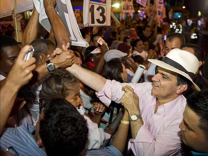 Supporters of Colombian presidential candidate for the Democratic Center party Oscar Ivan Zuluaga (R) greets supporters during a campaign rally in Cali, Colombia, on June 4, 2014. Colombian President Juan Manuel Santos, elected for the period 2010-2014, will face Zuluaga on June 15th in the runoff election. AFP PHOTO / LUIS ROBAYO