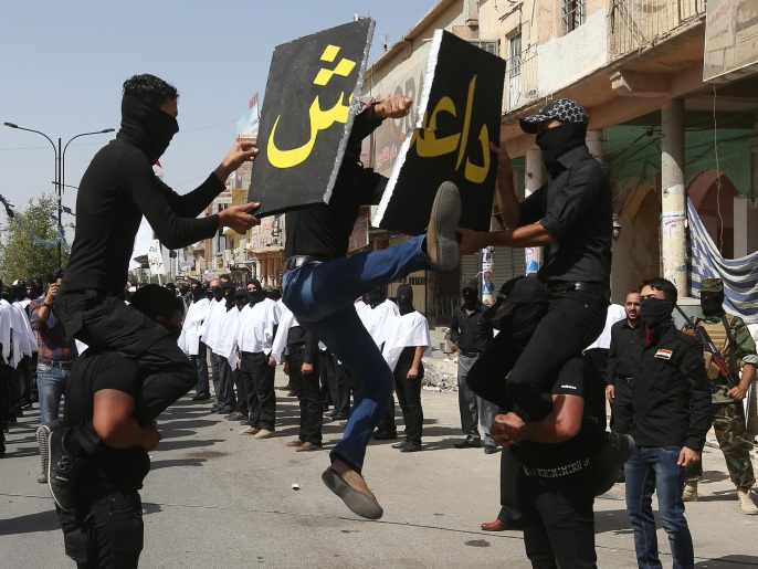 مشاركون في الاستعراض يحطمون لافتة تحمل اسم تنظيم الدولة الإسلامية (أسوشيتد برس)