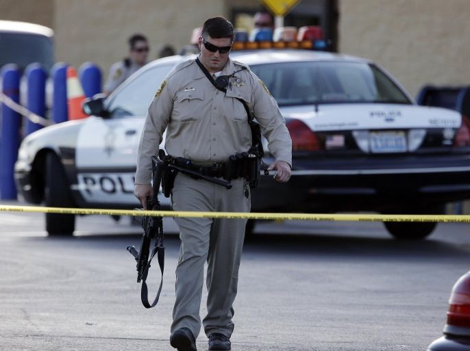 A Las Vegas police officer walks away from the scene of a shooting near a Wal-Mart, Sunday, June 8, 2014, in Las Vegas. A man and a woman ambushed two police officers eating lunch at a Las Vegas restaurant, fatally shooting them at point-blank range before fleeing to a nearby Wal-Mart where they killed a third person and then themselves in an apparent suicide pact, authorities said Sunday. (AP Photo/John Locher)