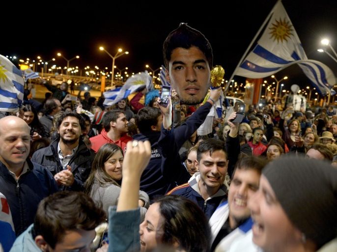 Fans of Uruguay's national soccer team await the arrival of Uruguay player Luis Suarez at Carrasco International Airport in the outskirts of Montevideo, Uruguay, Thursday, June 26, 2014. The Uruguay forward, widely regarded as one of the best players in the world, was banned by FIFA from all football for four months on Thursday for biting an Italian opponent in an incident that marred the team's victory and progression to the second round. (AP Photo/Matilde Campodonico)