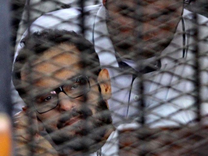 Detained American-Egyptian activist, Mohamed Sultan sits behind the bars of the accused dock during his trial on June 23, 2014 in the Egyptian capital Cairo. Sultan, who has been detained since August 2013 for participating in the sit-in at Rabaa-Al Adaweya Square supporting Morsi, is on hunger strike for 147 days. AFP PHOTO / STR