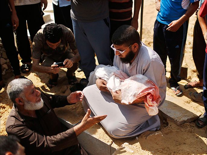 Palestinians bury the body of Palestinian boy Abdulrahamn Abed al-Nabi, 1, who medics said was killed in an Israeli air strike, during his funeral at a cemetery in the northern Gaza Strip July 24, 2014. Israel won a partial reprieve from the economic pain of its Gaza war on Thursday with the lifting of a U.S. ban on commercial flights to Tel Aviv, while continued fighting pushed the Palestinian death toll over 700. A truce remained elusive despite intensive mediation efforts. Israel says it needs more time to eradicate rocket stocks and cross-border tunnels in the Gaza Strip and Hamas Islamists demand the blockade on the enclave be lifted. REUTERS/Suhaib Salem (GAZA - Tags: POLITICS CIVIL UNREST CONFLICT) TEMPLATE OUT