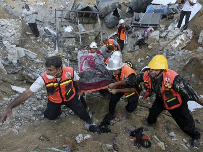 Palestinian rescue officers remove a body from the rubble of a building where at least 20 members of the Al Najar extended family were killed, including at least 10 children, by an Israeli strike in Khan Younis, in the southern Gaza Strip, Saturday, July 26, 2014, according to Palestinian health official Ashraf al-Kidra. A brief cease-fire Saturday in the Gaza war between Israel and Hamas militants allowed thousands to return home to see the destruction. (AP Photo/Eyad Baba)