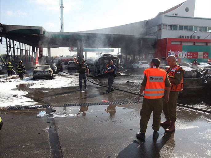 Israeli fire fighters extinguish vehicles destroyed by fire following a rocket fired from the Gaza Strip that hit a gas station in the city of Ashdod in southern Israel on July 11,2014.