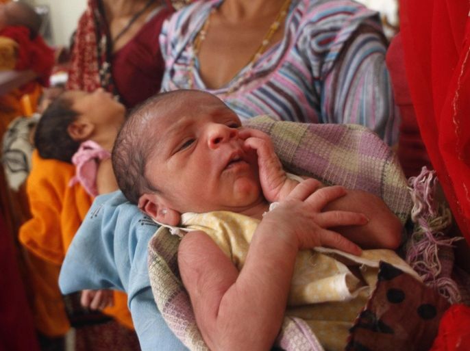 An infant rests in the arms of a woman at a government hospital on World Population Day in Ajmer, India, Friday, July 11, 2014. India is the second most populous country with 1.2 billion people next to China, with its capital being the second most populated city in the world. (AP Photo/Deepak Sharma)
