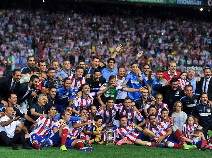 Atletico Madrid's players and staff pose on the pitch with the Super Cup trophy at the end of the Spanish Supercopa second-leg football match Atletico de Madrid vs Real Madrid CF at the Vicente Calderon Stadium in Madrid on August 22, 2014.